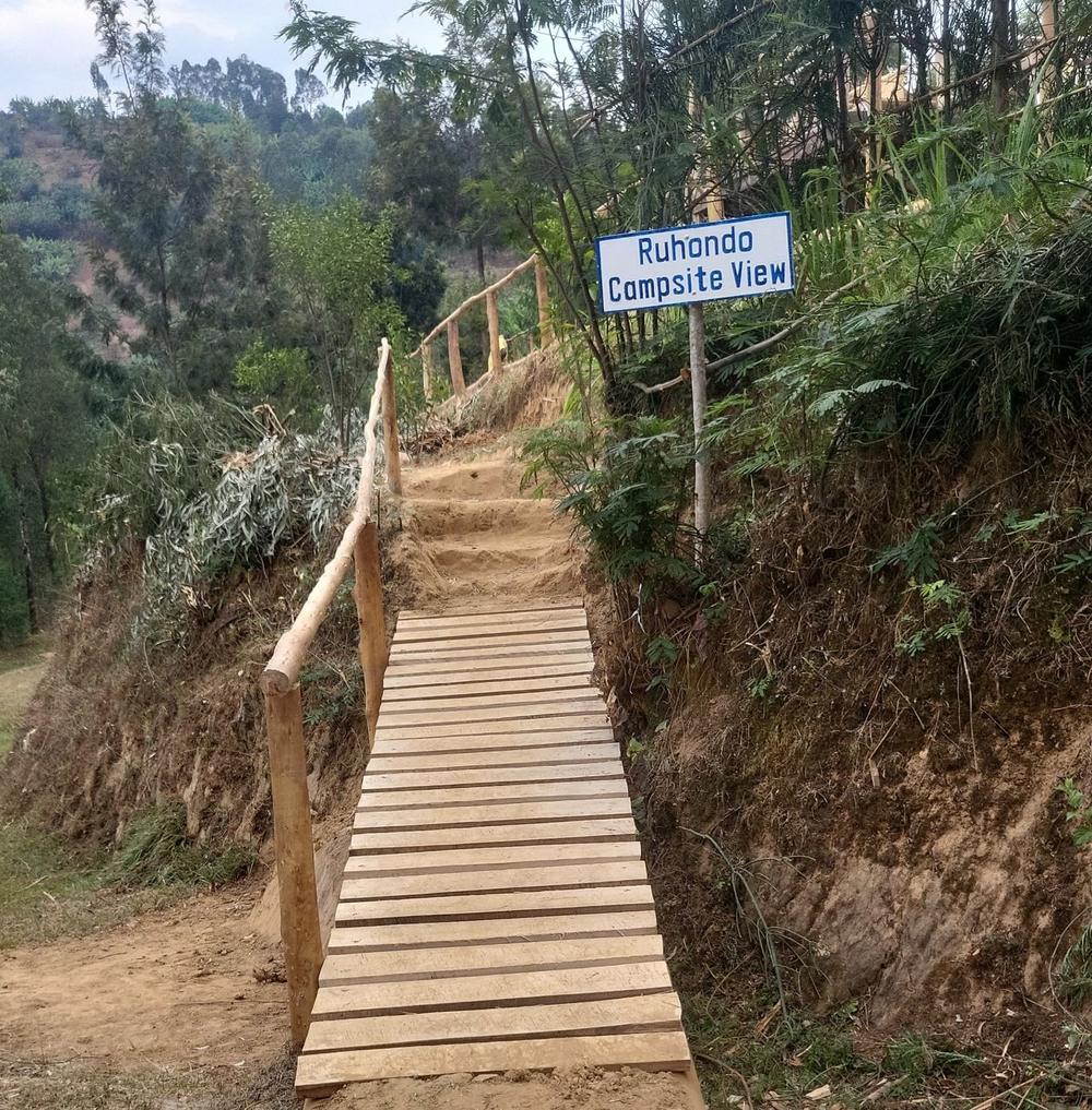 Wooden steps and a hand-painted sign reading Ruhondo Campsite View